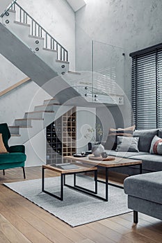 Stylish composition of living room interior. Grey sofa, green velvet armchair, coffee table and minimalist personal accessories.