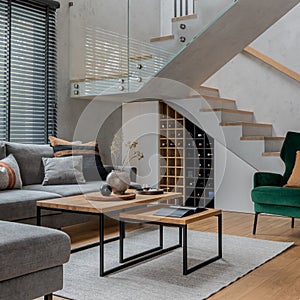 Stylish composition of living room interior. Grey sofa, green velvet armchair, coffee table and minimalist personal accessories.