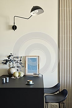 Stylish composition of modern small dining space interior. Black kitchen island and dining accessories. Neutral walls.