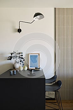 Stylish composition of modern small dining space interior. Black table, black and light wooden kitchen and dining accessories.