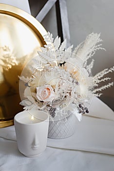 Stylish composition of preserved flowers and dried flowers in a light color scheme.