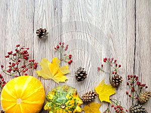 Stylish composition of pumpkins, autumn leaves and berries. Top view on wooden background. Autumn flat lay