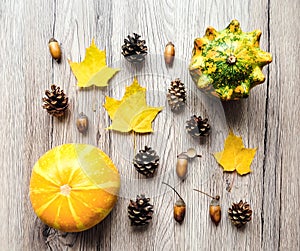 Stylish composition of pumpkins, autumn leaves, cones. Top view on wooden background. Autumn flat lay