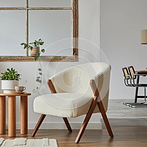 Stylish compositon of modern living room interior with frotte armchair, wooden commode, side table and elegant home accessories.