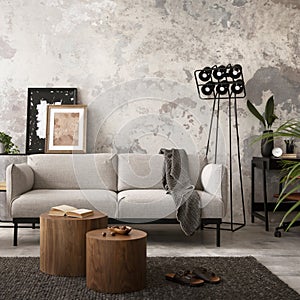 The stylish compostion at concrete living room interior with design gray sofa, wooden coffee table, desk and elegant personal