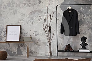 The stylish compostion at living room interior with mock up, concrete wall, bench, hanger with clothes and elegant personal photo