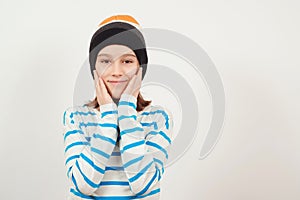 Stylish confident boy smiling over white background. Cute guy wearing woolen hat. Portrait of eleven years old boy