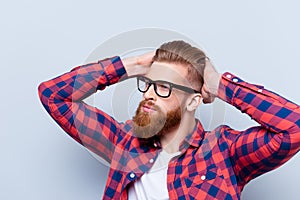 Stylish confident young bearded man in checkered shirt and glass