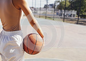 Stylish cool teen girl gathering at basketball court, playing basketball outdoors