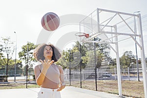 Stylish cool teen girl gathering at basketball court, playing basketball outdoors