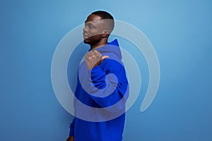 stylish cool young guy american with dark skin is dressed in a trendy sweatshirt with a hood on a studio background with