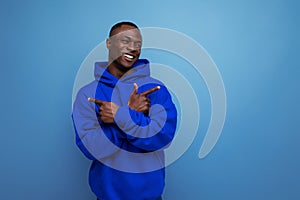 stylish cool young guy american with dark skin is dressed in a trendy sweatshirt with a hood on a studio background with