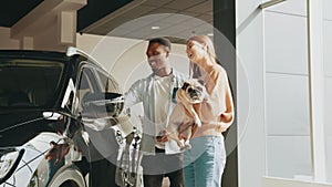 Stylish couple choosing new automobile while walking by luxury cars in car dealership. Young multi ethnic couple buying