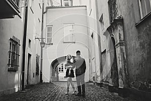 Stylish couple embracing in european city street on background of old architecture. Fashionable man and woman in love dancing with