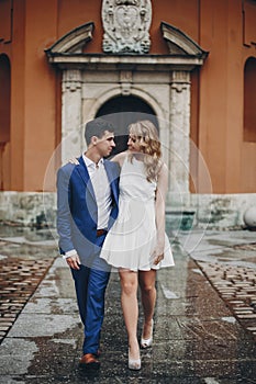 Stylish couple embracing together in european city street on background of old architecture. Fashionable man and woman in love