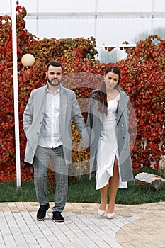 Stylish couple in gray coats walking in the autumn park. Happy sensual wedding couple. Romantic moments of newlyweds