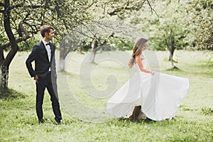 Stylish couple of happy newlyweds posing in the park on their wedding day