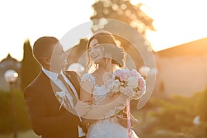 Stylish couple of happy newlyweds posing in the park on their wedding day. Perfect couple bride, groom funny joke