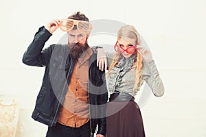 Stylish couple in huge orange glasses posing in studio. Man with nice beard and mustache hugging blond attractive girl