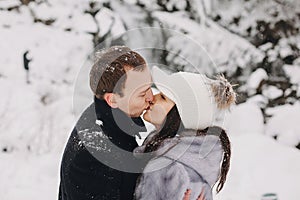 Stylish couple kissing in winter snowy mountains. Happy romantic