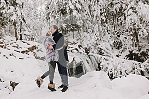 Stylish couple kissing in winter snowy mountains. Happy romantic