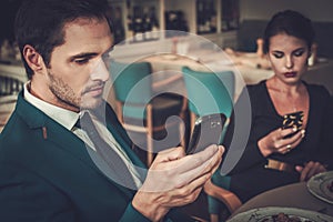 Stylish couple with mobile phones in a restaurant