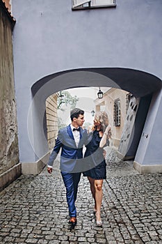 Stylish couple walking together in european city street on background of old architecture. Fashionable man and woman in love