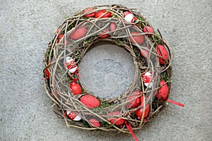 Stylish Easter holiday decor handmade wreath of red eggs twisted of dry twigs and moss for your home door decoration