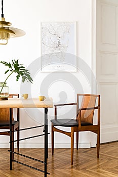 Stylish and eclectic dining room interior with mock up poster map, sharing table design chairs, gold pedant lamp.