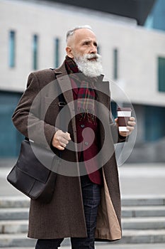 Stylish elderly man going to office, drinking coffee