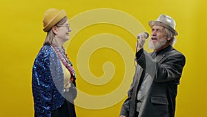 Stylish Elderly Woman On Yellow Background. She Is Wearing Hat And Glasses. Stylish Man With Beard In Hat. Man Singing