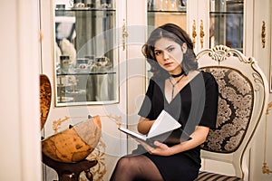 Stylish elegant brunette woman in beauty rich interior, wearing black dress