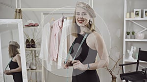 Stylish elegant slim woman in black dress and beret turning to camera and smiling. Portrait of confident positive