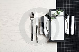 Stylish elegant table setting and blank card on wooden background, top view. Space