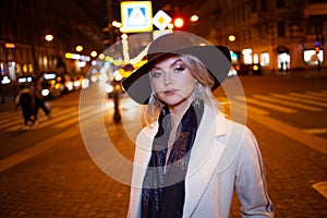 Stylish and elegant young woman in a beige coat and black hat on the city