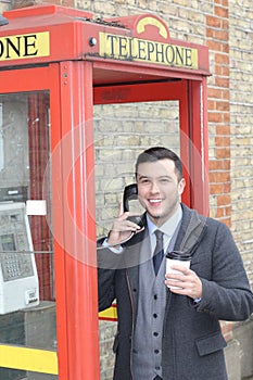 Stylish ethnic gentleman calling from vintage payphone