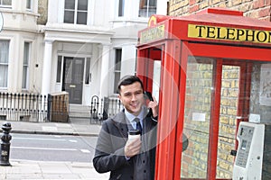 Stylish ethnic gentleman calling from vintage payphone