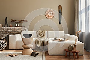 Stylish ethnic living room interior with design sofa, wooden stool, moroccan shelf, carpet decor, a lot of elegant decoration.