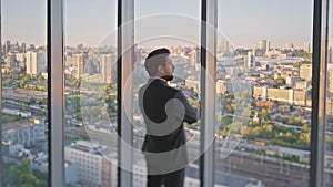 Stylish executive looking window rear view. Pensive businessman admiring city