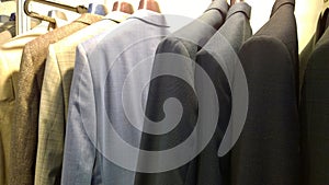 Stylish expensive men`s business suits for sale. Clothes on hangers. Fashion for managers and businessmen concept. Premium store.