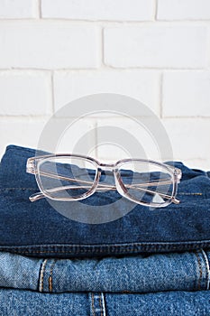 stylish eye glasses on a stack of jeans