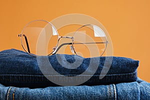 stylish eye glasses on a stack of jeans