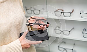 Stylish eyeglasses holding in hands. Eyewear modern glasses with stylish lens.