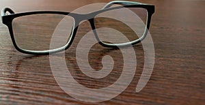 Stylish eyeglasses on office table on blurred background