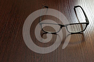 Stylish eyeglasses on office table on blurred background