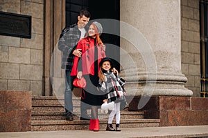 Elegante familia de tres camina través de otono la ciudad posando fotógrafo . papá madre en 