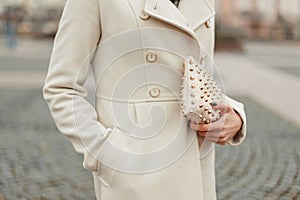 Stylish fashion handbag in a hand. Fashionable woman in a coat