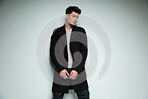 stylish fashion man in black coat looking down side and posing