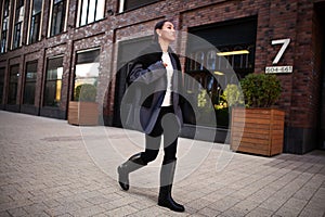 Elegante moda una mujer camina abajo calles en tamanos de gran tamano chaqueta de sport negro polainas a rodilla alto goma zapatos 