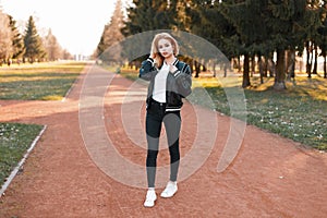 Stylish fashionable girl in a jacket, jeans and white shoes